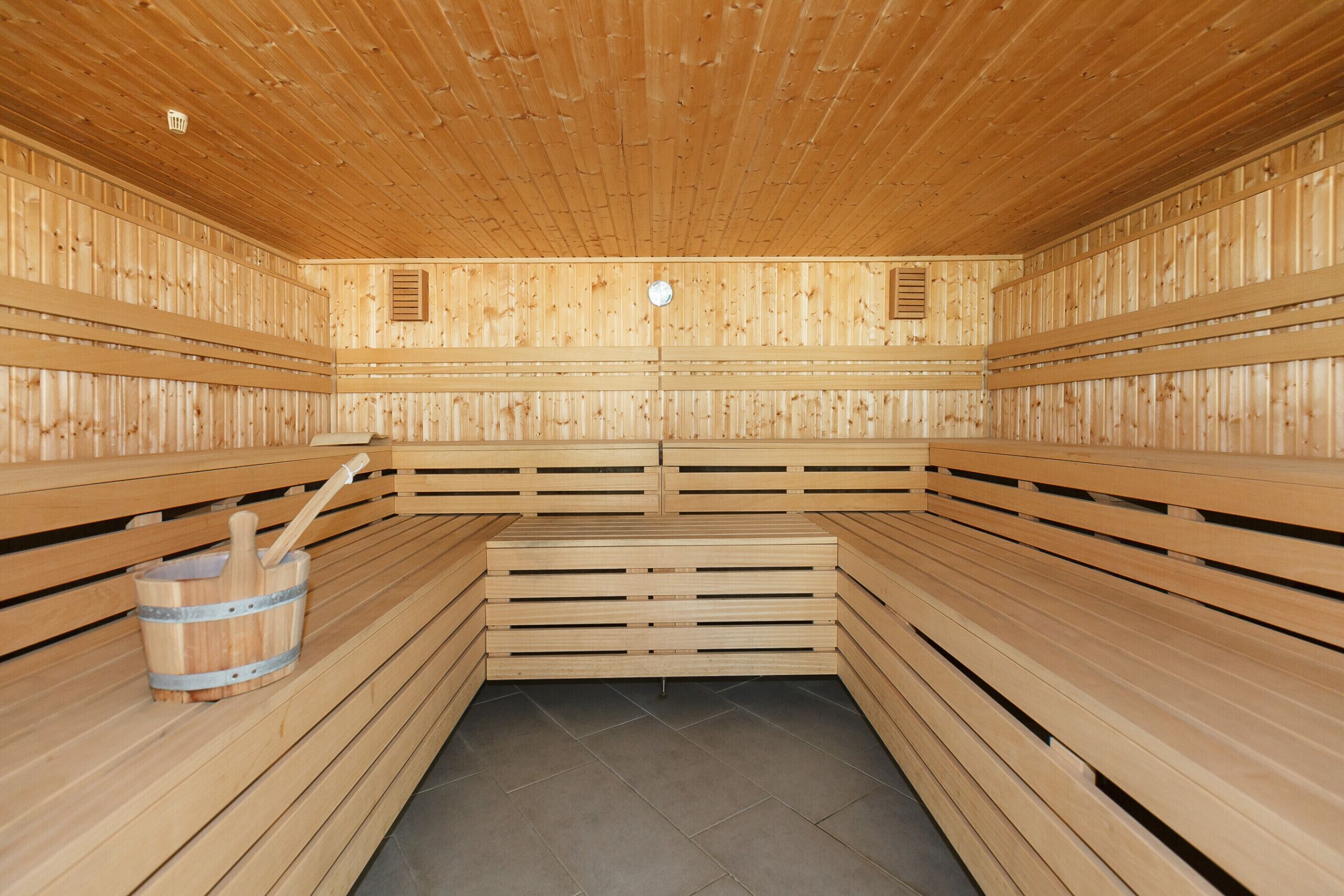 Eine Sauna mit Holzbänken und einem Eimer mit Bürste.