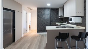 A modern kitchen with a built-in microwave, stainless steel refrigerator, and a bar area with two stools. - Apartment SOL CAMBRILS PARK with SPA area (Cambrils)