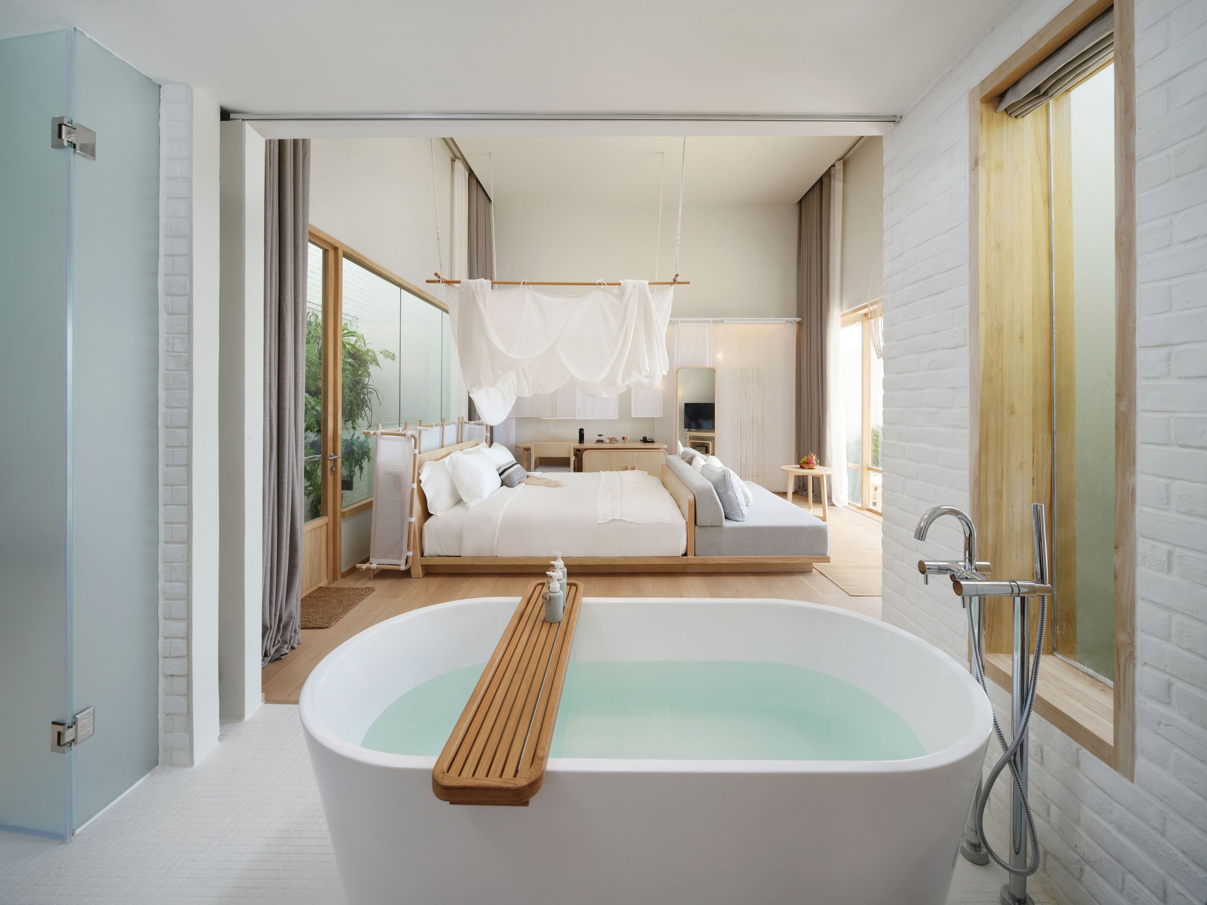 Un dormitorio moderno con una bañera grande, una cama con dosel y vistas al exterior.