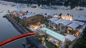 Un resort con piscina, un puente y varios edificios de arquitectura diferenciada.