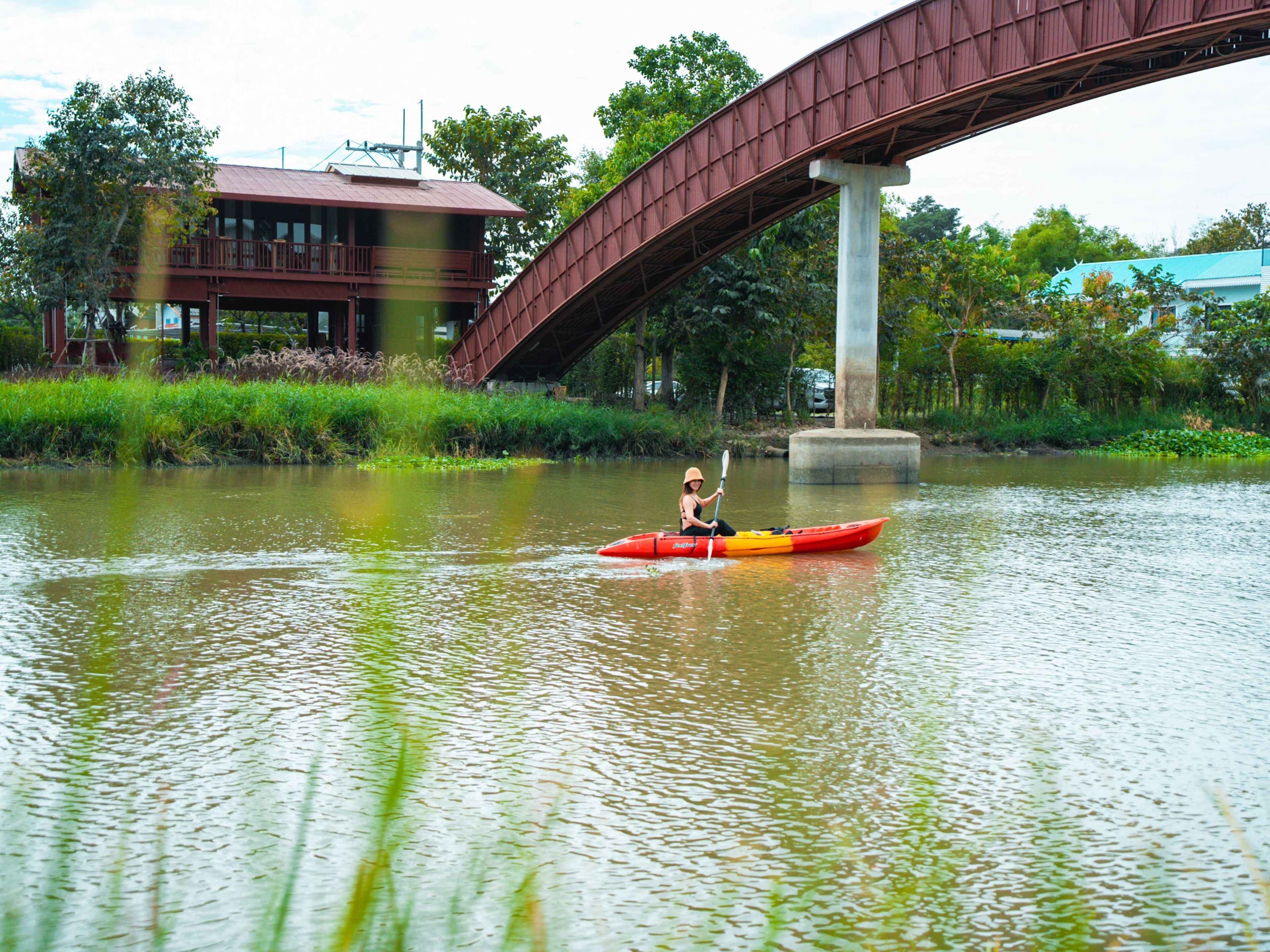 A person kayaking on a river with a bridge in the background.