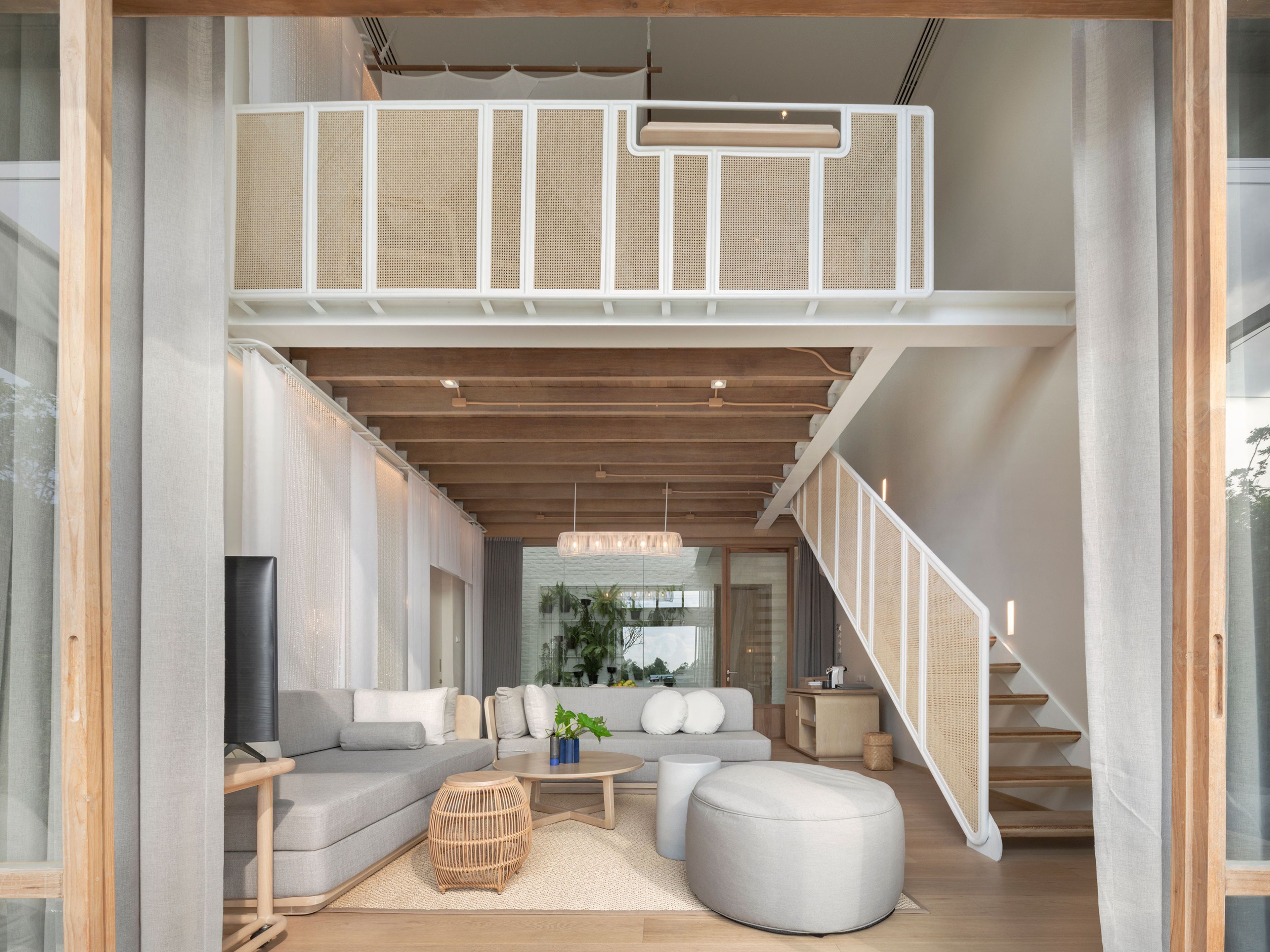 Un amplio salón con techo alto, una escalera y vistas al exterior.