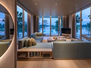 A modern living room with a large TV, comfortable seating, and a view of a body of water. - sala bang pa-in, a Member of Design Hotels (Bang Pa-in)