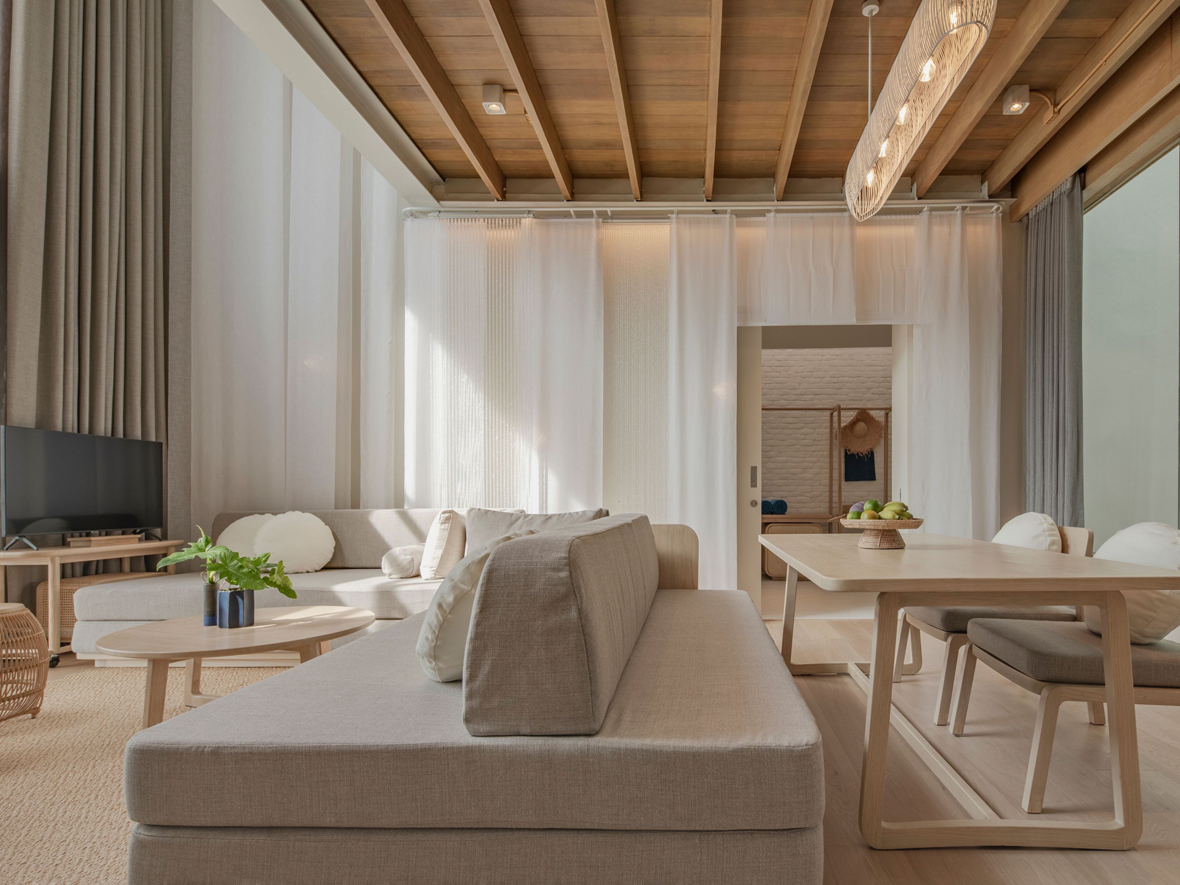 Ein modernes Wohnzimmer mit Sofa, Couchtisch, Fernseher und Essbereich.