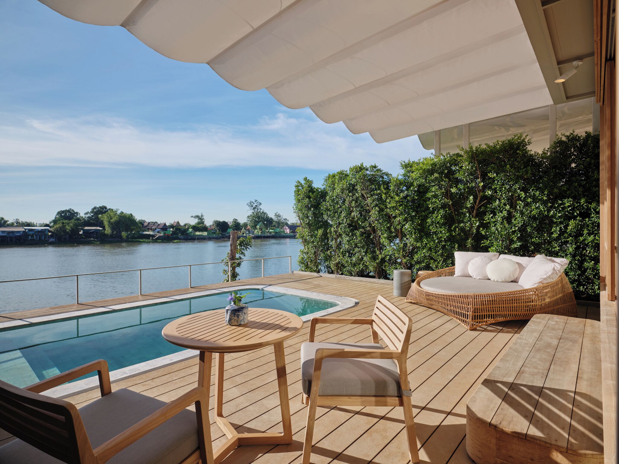 Une terrasse en bois avec une piscine, des chaises longues et une table.