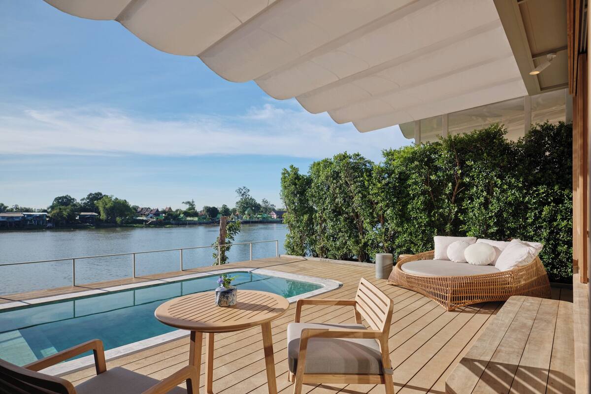 A wooden deck with a pool, lounge chairs, and a table.
