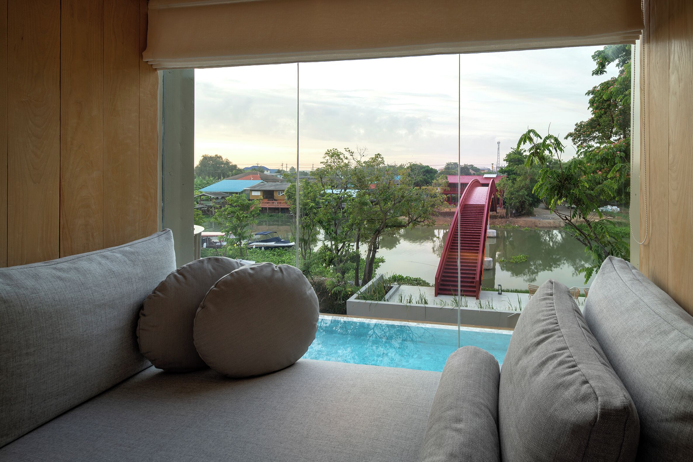 Une chambre avec vue sur une piscine, un bâtiment rouge et de la verdure.
