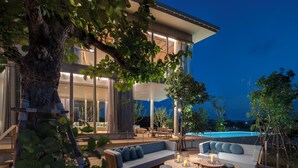 Un espacio exterior moderno con piscina, terraza de madera y zonas de estar.