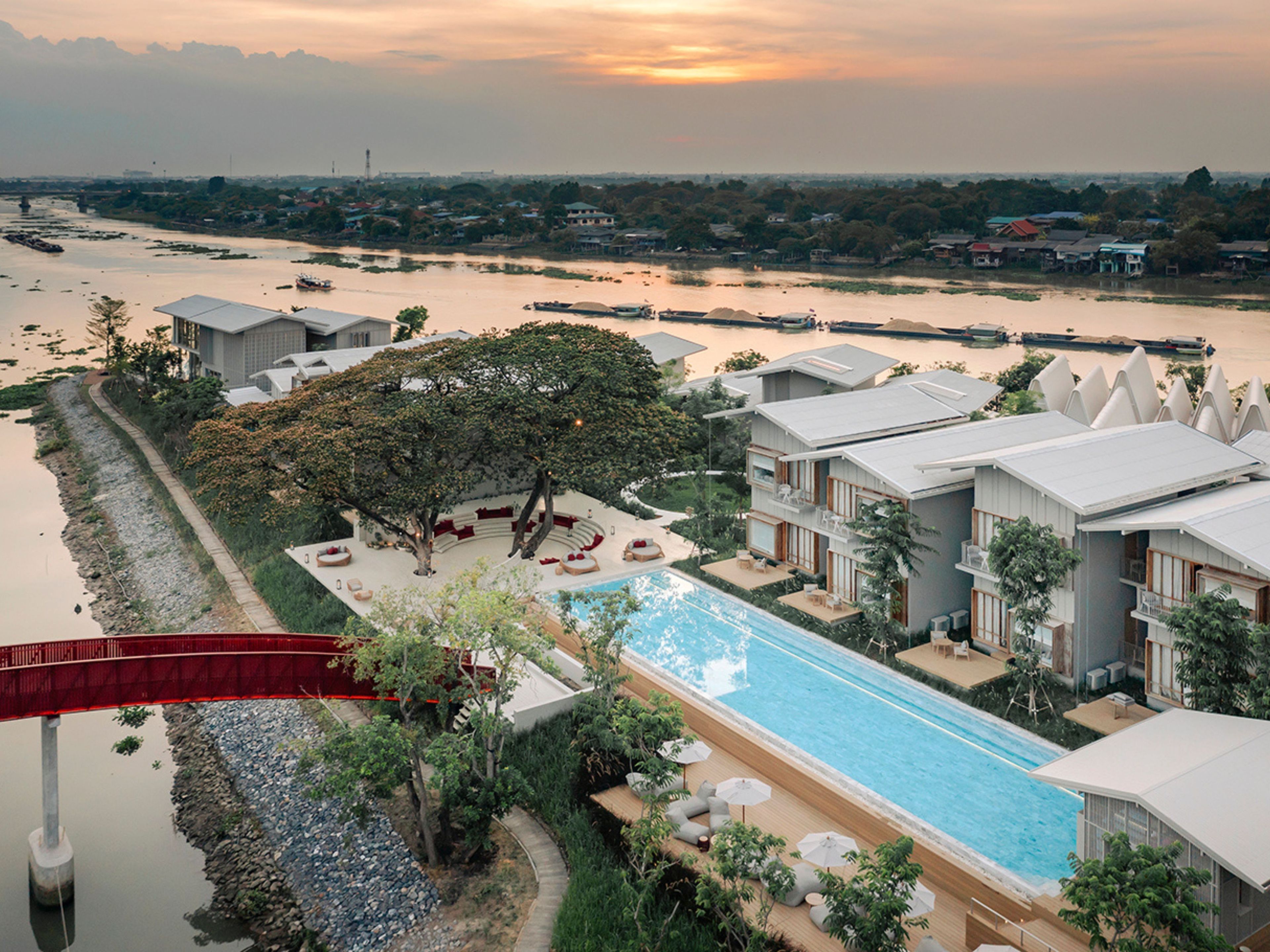 A resort with a swimming pool, a red slide, and a view of a river.