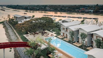 A resort with a swimming pool, a red slide, and a view of a river.