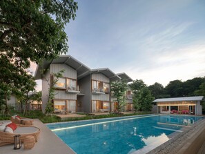 A modern hotel with a swimming pool, outdoor seating, and a view of the surrounding trees. - sala bang pa-in, a Member of Design Hotels (Bang Pa-in)