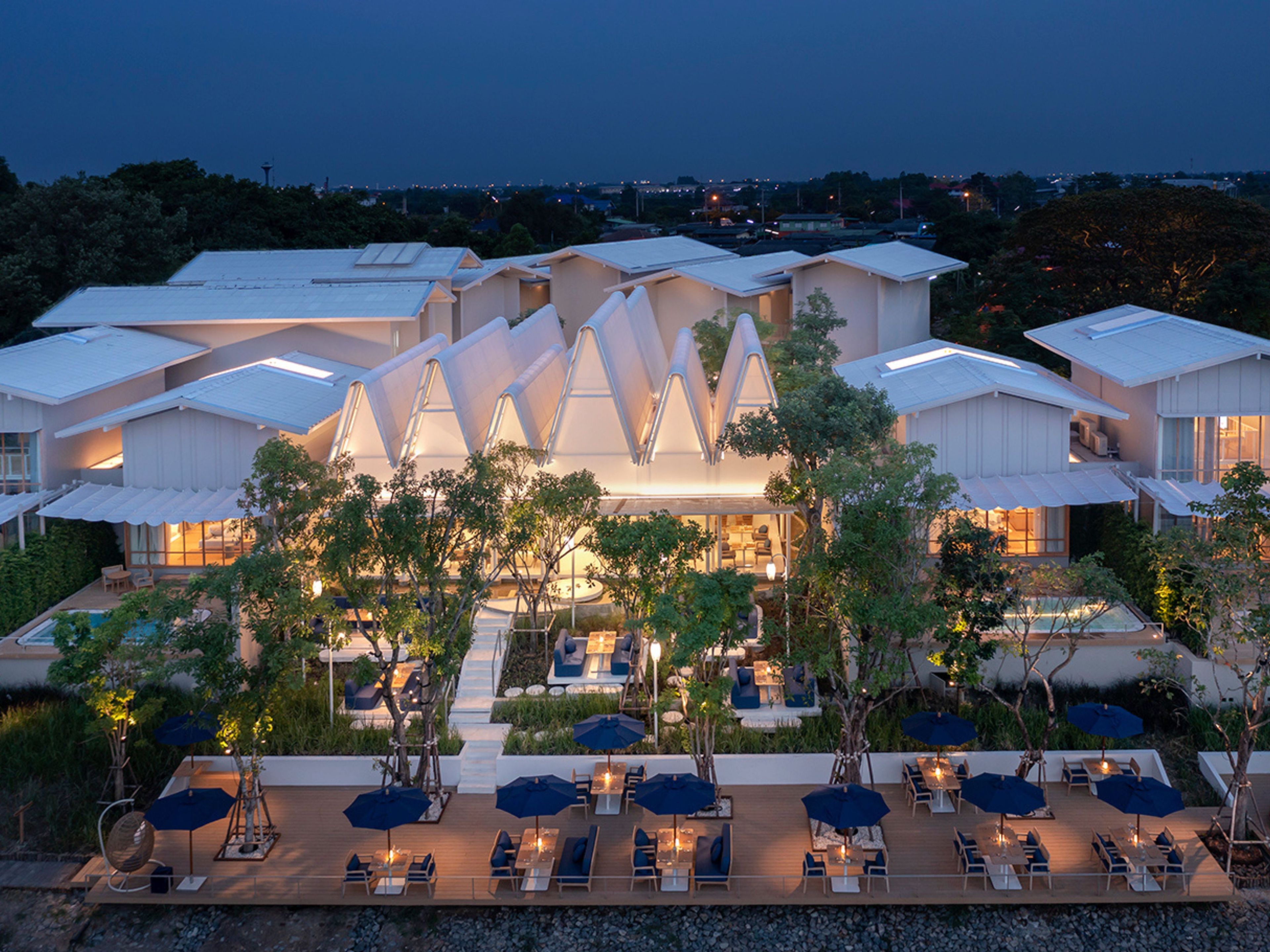 A modern hotel with a unique architectural design, featuring a central atrium and outdoor seating area.