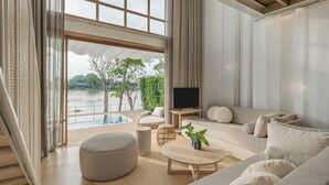 Una sala de estar moderna con un sofá, un reposapiés, una mesa de centro y un televisor.