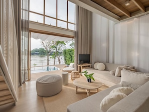 A modern living room with a large window, a flat-screen TV, a sofa, and a round coffee table. - sala bang pa-in, a Member of Design Hotels (Bang Pa-in)