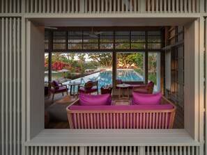 A modern outdoor seating area with a pool view, featuring a sofa and chairs with cushions. - sala bang pa-in, a Member of Design Hotels (Bang Pa-in)