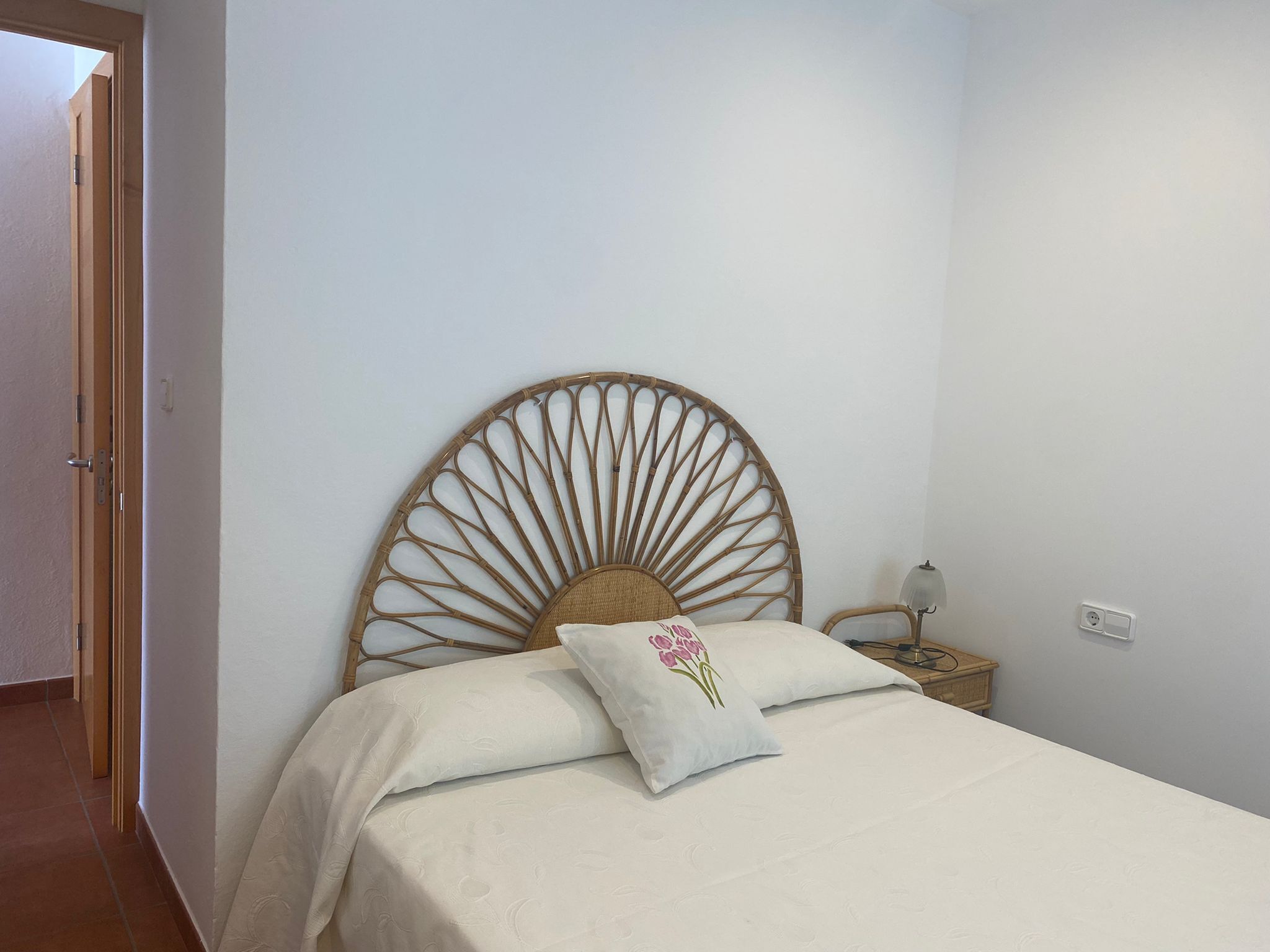 A bedroom with a bed, a nightstand, and a wall-mounted lamp.