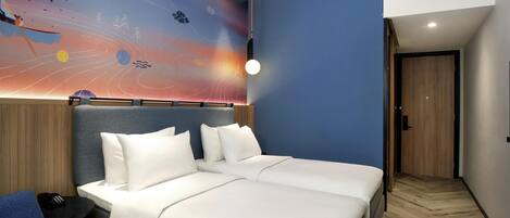 A modern hotel room with a large bed, a desk, and a chair. The room features a unique wall mural depicting a cosmic scene.