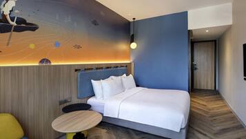 A modern hotel room with a large bed, a small round table, and a colorful mural on the wall.