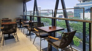 A modern restaurant with high ceilings, large windows, and a view of the cityscape. - Ibis Styles Semarang Simpang Lima (Semarang)