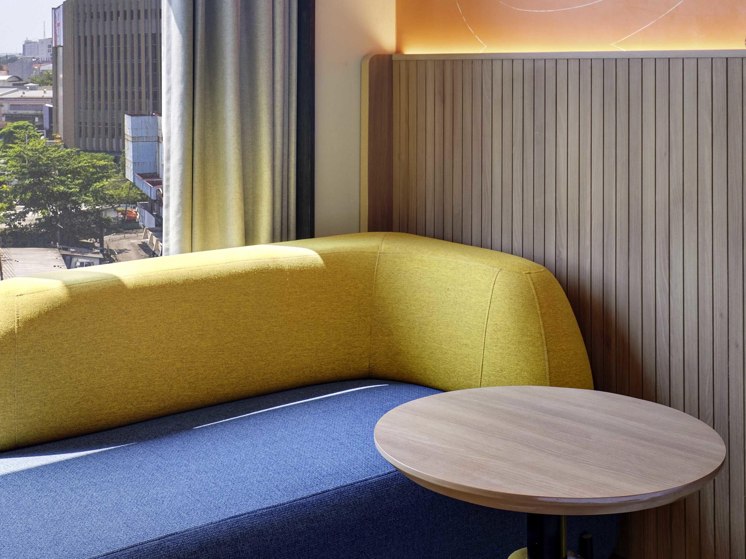 Un rincón amoblado con un sofá amarillo y una mesa redonda de madera.