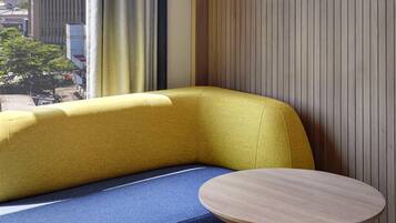 Un rincón amoblado con un sofá amarillo y una mesa redonda de madera.