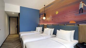 Habitación de hotel con dos camas, piso de madera, pared azul de acento y un mural con una persona y un atardecer.