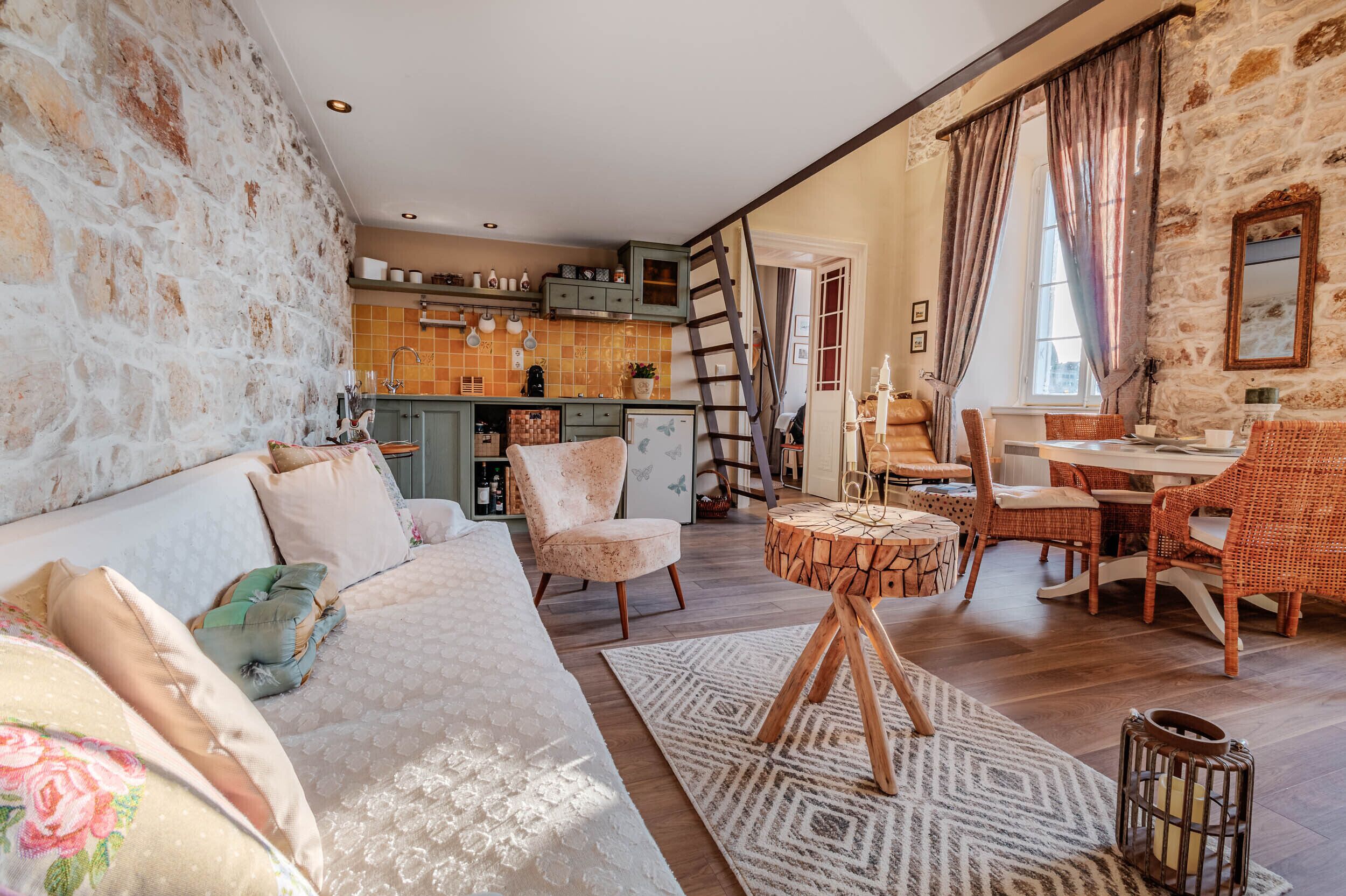 A cozy living room with a sofa, chairs, a coffee table, and a kitchen in the background.