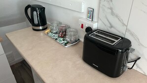 Una kitchenette con cafetera, tostadora y recipientes de cápsulas de café.