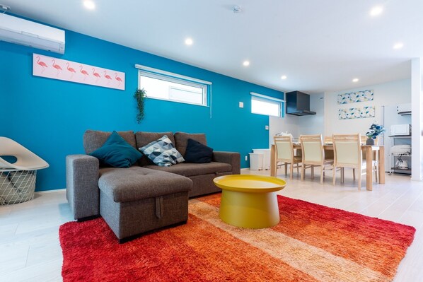 A modern living room with a grey sofa, a yellow coffee table, and a red rug.