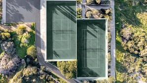 An aerial view of a tennis court complex with two courts, surrounded by greenery and a road. - Casa Saudade, semidetached house with Jacuzzi near Ferragudo (Carvoeiro)
