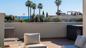 A rooftop terrace with outdoor furniture, a barbecue area, and a view of palm trees and the sea. - Casa Saudade, semidetached house with Jacuzzi near Ferragudo (Carvoeiro)