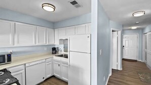 A kitchen with white cabinets, a microwave, a coffee maker, and a refrigerator.