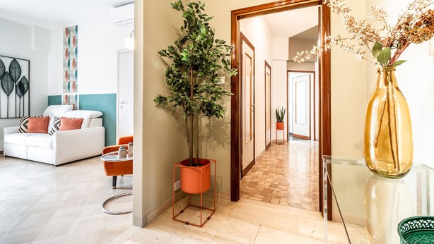 En moderne stue med en hvid sofa, en orange lænestol og en potteplante.