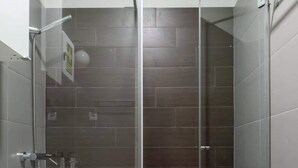 Un baño moderno con ducha envuelta en vidrio, un inodoro y un lavamanos.
