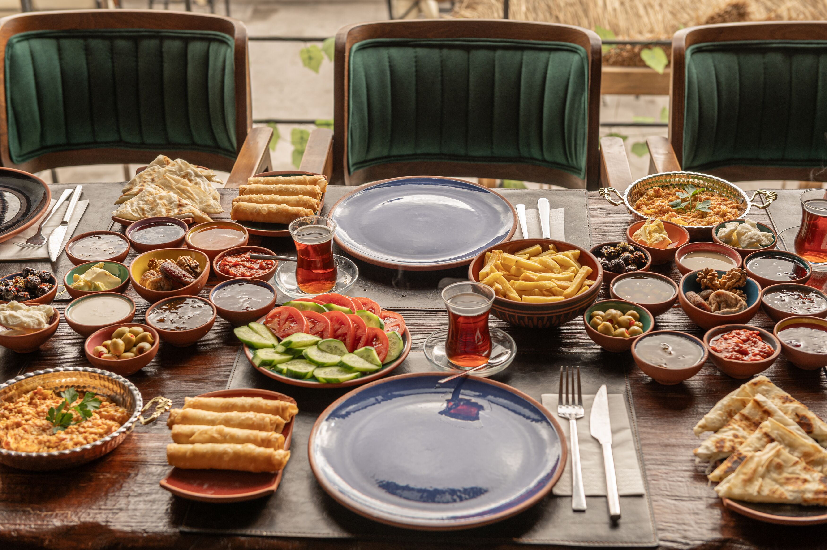 A table set with various dishes, including flatbreads, salads, and bowls of dips, suggesting a communal meal setting.