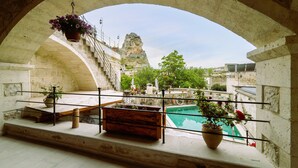 A balcony with a stone railing, a wooden bench, and a hanging flower pot. - Capp Royal Cave Hotel (Ürgüp)