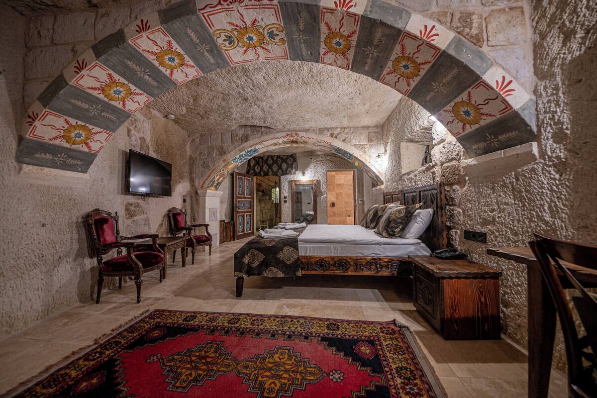 A traditional room with a bed, a television, and a red carpet.