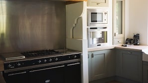 A kitchen with a gas stove, oven, microwave, and a coffee maker on the counter.
