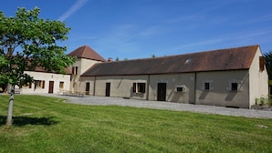 A building with a tiled roof, multiple doors, and a paved courtyard.