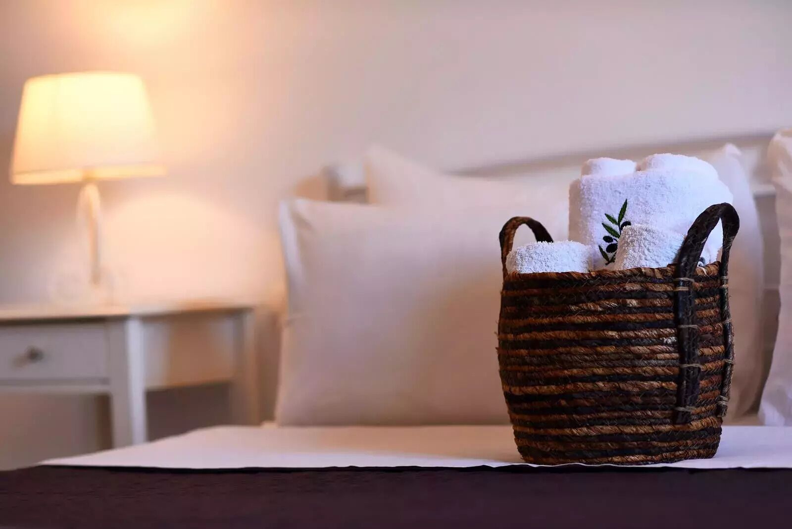 A wicker basket with towels on a bed in a hotel room.