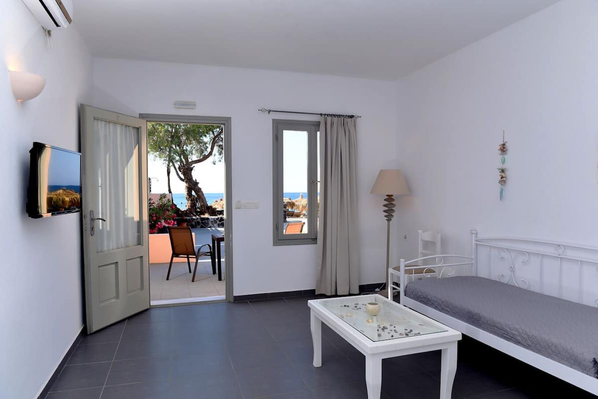 Una habitación con cama, mesa, televisión y vista a la playa.