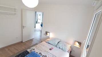 A bedroom with a bed, bedside lamps, a door, and a view of a hallway.