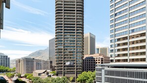 A tall, cylindrical building with multiple floors, surrounded by other high-rise buildings and trees.