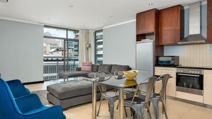 A modern kitchen with a dining area, large windows, and a view of the city.