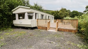 Una casa móvil con un porche pequeño y una valla de madera.