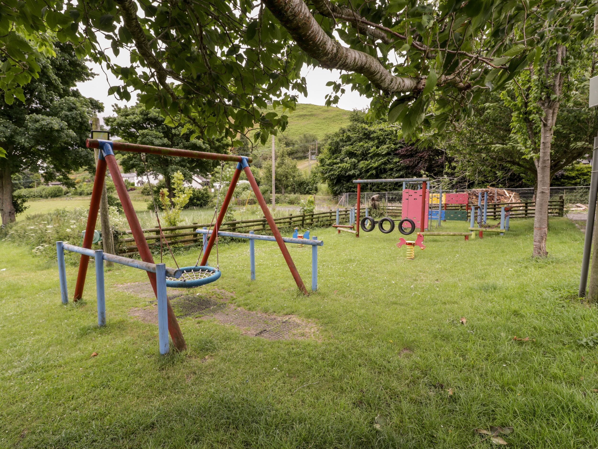 Un parque infantil con columpios, un neumático colgante y una estructura para escalar.