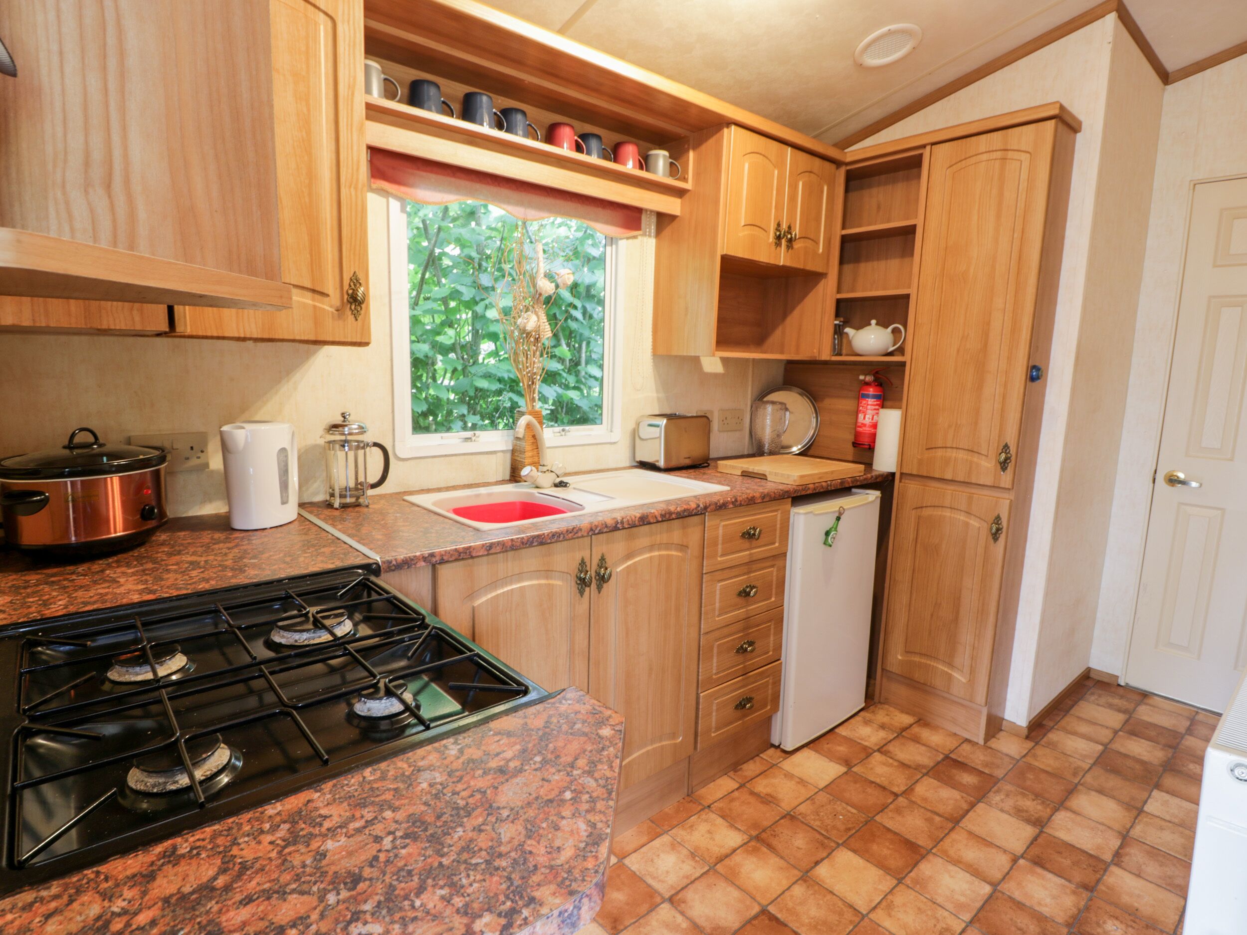 A compact kitchen with a gas stove, a sink, and wooden cabinets.