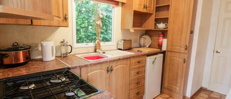 A compact kitchen with a gas stove, a sink, and wooden cabinets.