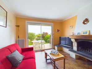 A living room with a red sofa, a wooden coffee table, a TV, and a fireplace.