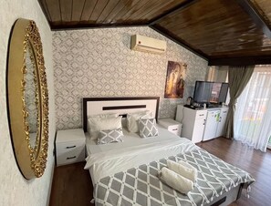 A bedroom with a bed, nightstands, a TV, and an air conditioning unit.